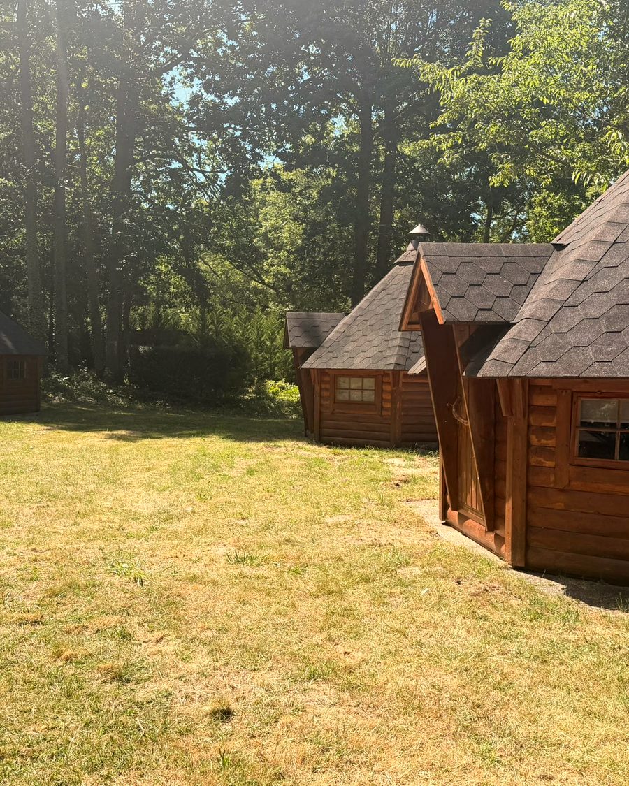 Cabanes en bois rondes des Cabanes de Condé, posées sur l'herbe entre les arbres