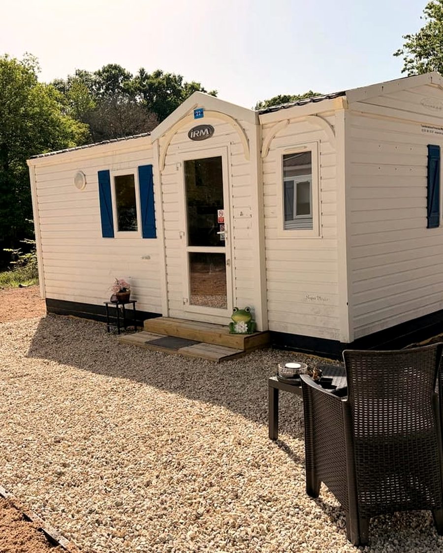 Mobil-home des Cabanes de Condé avec volets bleus et terrasse en gravier